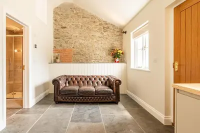 a leather couch in a hallway with a brick wall at Romantic and stylish retreat in Falmouth