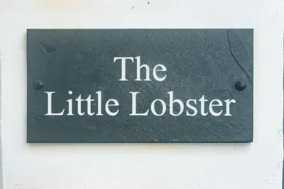 a sign that reads the little lobster on a wall at The Little Lobster in Porthleven