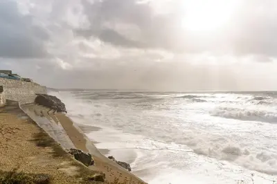 a beach with waves and the ocean on a cloudy day at The Little Lobster in Porthleven