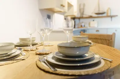 a wooden table with plates and wine glasses on it at The Little Lobster in Porthleven