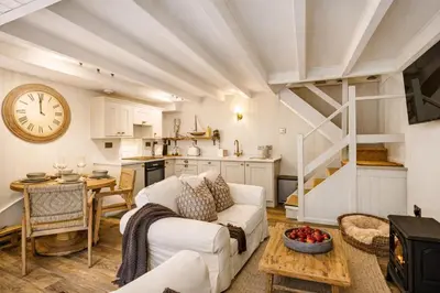 a living room with a couch and a clock on the wall at The Little Lobster in Porthleven