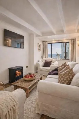 a living room with white furniture and a fireplace at The Little Lobster in Porthleven