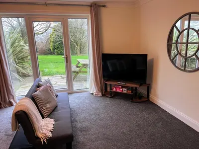 a living room with a couch and a flat screen tv at Countryside Converted Barn and Cottages Near Newquay in Saint Enoder