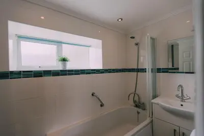 a bathroom with a tub and a sink and a window at The Stable Near St Ives Beaches Dog Friendly in St Ives