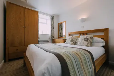 a bedroom with a large bed with a wooden headboard at The Stable Near St Ives Beaches Dog Friendly in St Ives