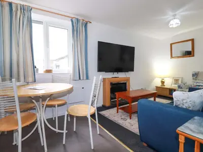 a living room with a table and a blue couch at Seaside Apartment in Looe