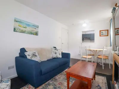 a living room with a blue couch and a table at Seaside Apartment in Looe