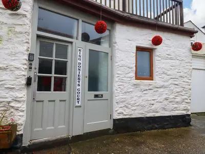 a white building with a white door and red balls at Seaside Apartment in Looe