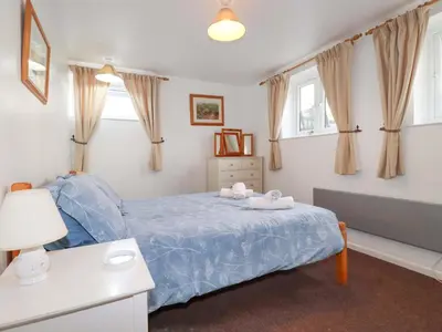 a bedroom with a bed with a blue comforter at Seaside Apartment in Looe