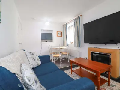 a living room with a blue couch and a tv at Seaside Apartment in Looe