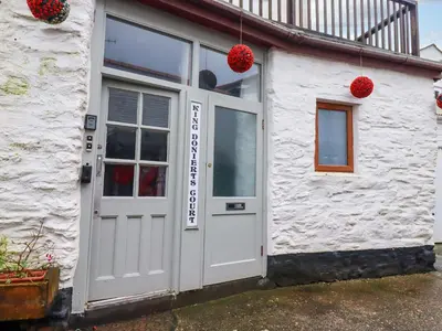 a white building with a white door and red balls at The Penthouse in Looe