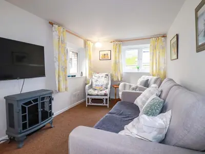 a living room with a couch and a flat screen tv at The Penthouse in Looe
