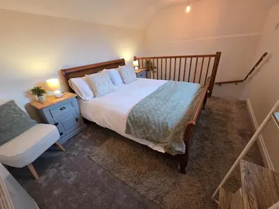 a bedroom with a large bed and a chair at Cosy Cornwall Cottage with Private Garden in Bodmin