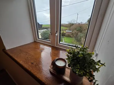 a room with a window with a clock and a plant at Cosy Cornwall Cottage with Private Garden in Bodmin
