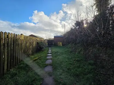 a backyard with a fence and a grass yard at Cosy Cornwall Cottage with Private Garden in Bodmin