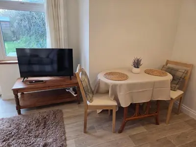 a living room with a table and a television at Cosy Cornwall Cottage with Private Garden in Bodmin