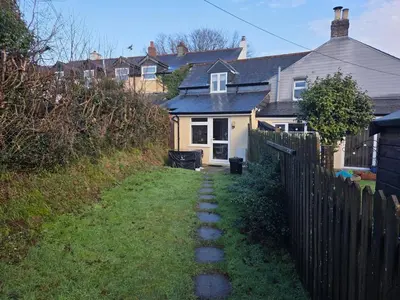 a house with a fence next to a yard at Cosy Cornwall Cottage with Private Garden in Bodmin