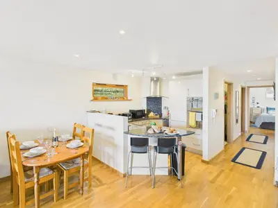 a kitchen and dining room with a table and chairs at 1 Arvor – Two-Bedroom Apartment with Parking at Maenporth Beach! Cornwall in Falmouth