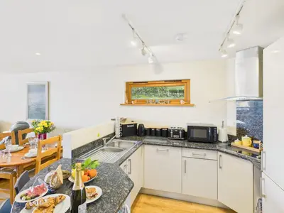 a kitchen with a table with plates of food on it at 1 Arvor – Two-Bedroom Apartment with Parking at Maenporth Beach! Cornwall in Falmouth