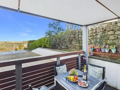 a table with a bowl of fruit on a balcony at 1 Arvor – Two-Bedroom Apartment with Parking at Maenporth Beach! Cornwall in Falmouth