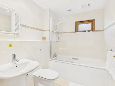 a white bathroom with a sink and a tub and a toilet at 1 Arvor – Two-Bedroom Apartment with Parking at Maenporth Beach! Cornwall in Falmouth