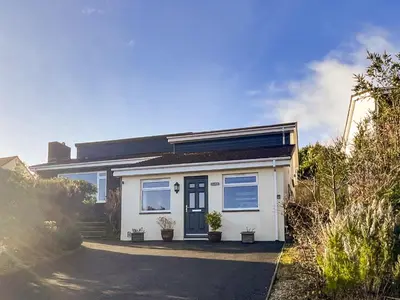 a white house with a blue door on a street at Hillside in St Austell