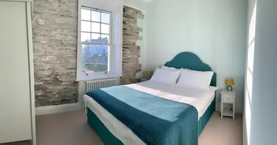 a bedroom with a bed with a blue headboard and a window at No 1 Exbury Padstow in Padstow