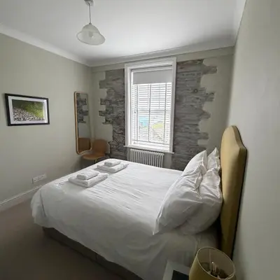 a bedroom with a white bed and a brick wall at No 1 Exbury Padstow in Padstow