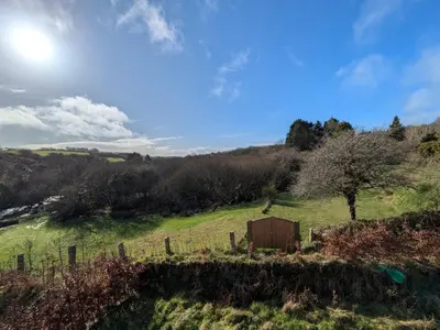 a field with a fence and a tree at Cober Riverside Retreat - Luxury Barn Apartment in The Heart of Cornwall in Wendron