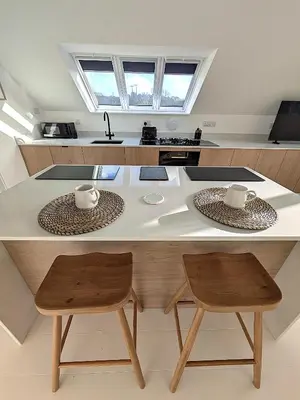 a kitchen with a large white table and two chairs at Cober Riverside Retreat - Luxury Barn Apartment in The Heart of Cornwall in Wendron