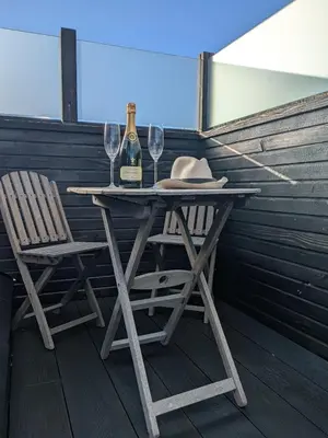 a table with two glasses of wine and two chairs at Cober Riverside Retreat - Luxury Barn Apartment in The Heart of Cornwall in Wendron