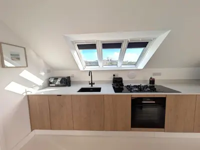 a kitchen with a stove and a sink and two windows at Cober Riverside Retreat - Luxury Barn Apartment in The Heart of Cornwall in Wendron