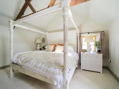 a bedroom with a white bed with a white canopy at Bospebo Cottage in Camborne