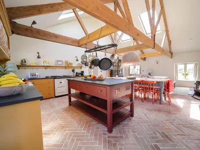 a kitchen with wooden ceilings and a kitchen island with a table at Bospebo Cottage in Camborne