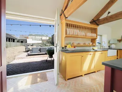 a kitchen with yellow cabinets and a patio at Bospebo Cottage in Camborne