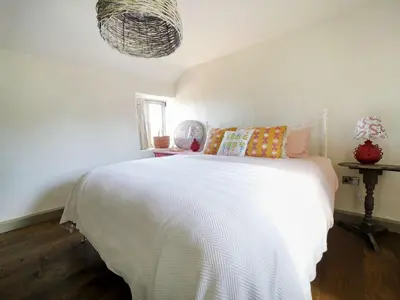 a bedroom with a bed with a white comforter at Bospebo Cottage in Camborne