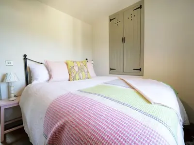 a bedroom with a bed with a pink and white blanket at Bospebo Cottage in Camborne