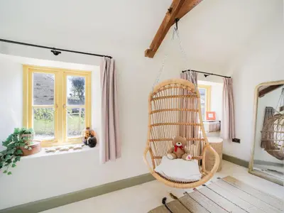 a hanging rattan chair in a room with a window at Bospebo Cottage in Camborne