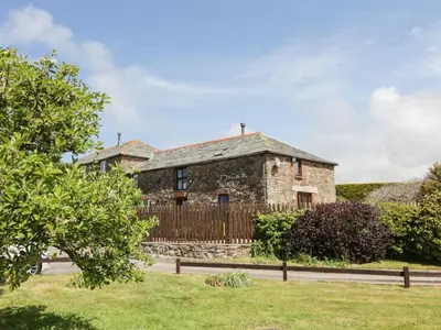 an old stone house with a wooden fence at Applestore in Wadebridge
