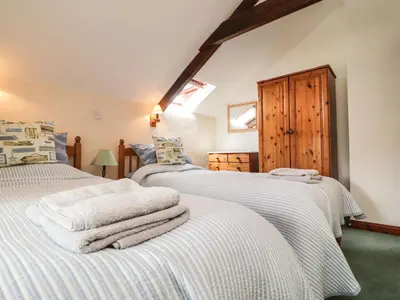 two beds in a room with white sheets at Applestore in Wadebridge