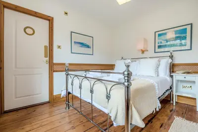 a bedroom with a bed with white sheets and a door at 2 Bed in Widemouth Bay oc-s34972 in Widemouth Bay