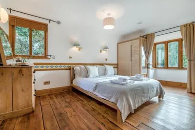 a bedroom with a large bed with wooden floors and windows at 2 Bed in Widemouth Bay oc-s34972 in Widemouth Bay