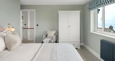 a bedroom with a white bed and a window at Luxury seaside home - 5 mins walk to beach - hot tub in Downderry