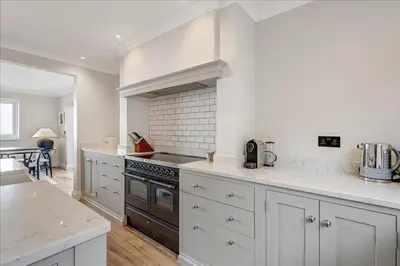 a kitchen with white cabinets and a stove top oven at Luxury seaside home - 5 mins walk to beach - hot tub in Downderry
