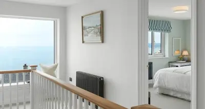 a white bedroom with a bed and a window at Luxury seaside home - 5 mins walk to beach - hot tub in Downderry