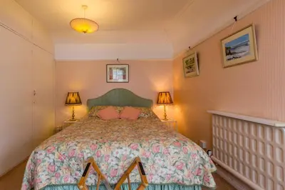 a bedroom with a bed with pink walls and two lamps at Porthallow Lodge 350m to SWCP Talland Bay Retreat in Talland