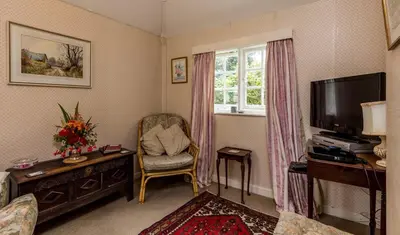 a living room with a tv and a chair and a window at Porthallow Lodge 350m to SWCP Talland Bay Retreat in Talland