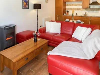 a living room with a red couch and a wood stove at Dune Cottage - Uk48934 in Saint Erth