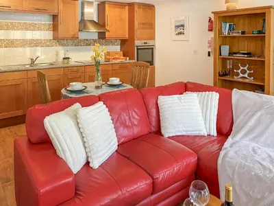 a red leather couch with white pillows in a kitchen at Dune Cottage - Uk48934 in Saint Erth