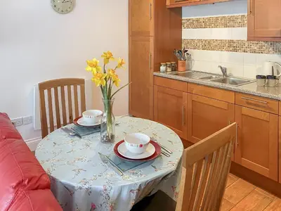 a kitchen with a table with a vase of flowers on it at Dune Cottage - Uk48934 in Saint Erth